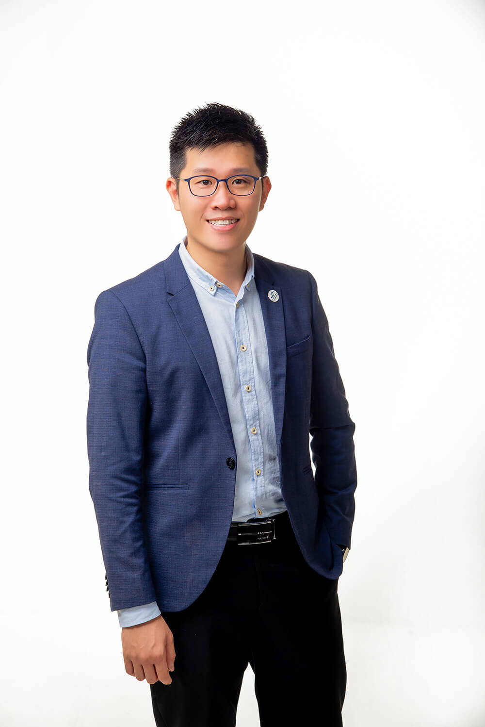 Wong JY, smiling young optometrist in a blue blazer and eyeglasses, embodying modern optical care professionalism.