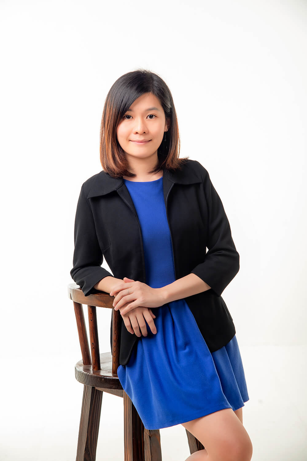 Tze Wen, confident female optometrist in a blue dress and black blazer, exemplifying the professional care at an optical clinic.