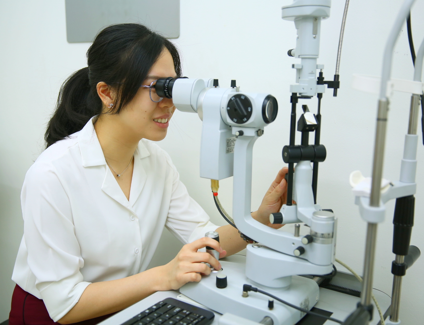 Optometrist performing eye screening on patient with advanced diagnostic equipment in clinic